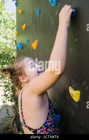 Seitenansicht des Kindes in Sportbekleidung Kletterwand mit künstlichen Rockt beim Training im Fitnessstudio und am Wochenende Stockfoto