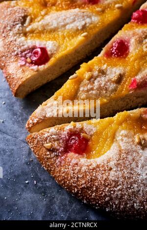 Nahaufnahme einiger Stücke einer Coca de Sant Joan, ein typischer süßer flacher Kuchen aus Katalonien, Spanien, gegessen an der St. Johns Eva, auf einer grauen Steinoberfläche Stockfoto