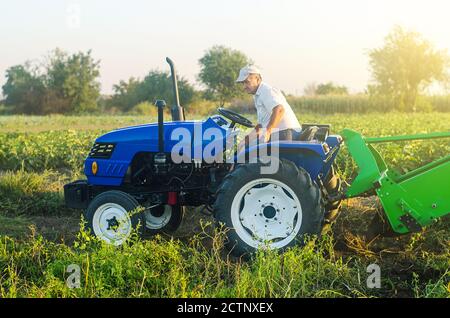 Ein Landwirt auf einem Traktor bereitet sich darauf vor, das Feld zu betreten und mit der Ernte zu beginnen. Landwirtschaft und Ackerland. Kartoffeln im Herbst ernten. Beschleunigen Sie die Arbeit mit Techno Stockfoto