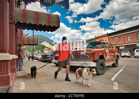 Man Walking with dogs, Checker Taxicab, dient als Werbung für lokale Grumpy's Restaurant auf Greene Street, Silverton, Colorado, USA Stockfoto