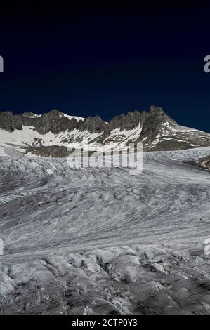 Der tief zerklüftete Rhône-Gletscher fließt auf etwa 30 bis 40 m (100 bis 130 ft) pro Jahr von Schneefeldern an den Hängen des 3,383 m (11,099 ft) Tieralplistocks bis zu einem Punkt unterhalb des Furka-Passes im Kanton Wallis, Schweiz, Wo das Eis in einem grünen See auf einer Höhe von etwa 2,208 m (7,244 ft) schmilzt. Das Schmelzwasser donnert tief unten in das Talbecken und beginnt die 813 km (505 Meilen) lange Reise des Flusses Rhône zum Mittelmeer über Südfrankreich und das Camargue-Delta. Stockfoto
