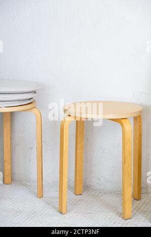 Holzhocker im minimalistischen Stil nahe der weißen Wand des kleinen Kaffeehafes. Stockfoto