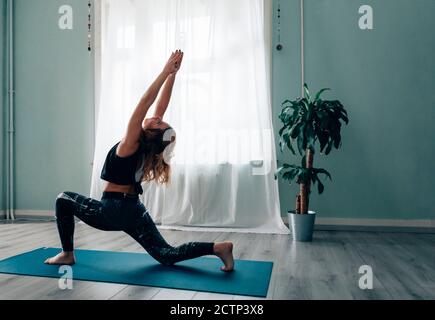 Frau in Sportkleidung, die Yoga-Übungen mit erhobenen Armen macht Und die Hände umklammten, während sie ihren Kopf nach hinten streckten und schauten Nach oben Stockfoto