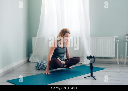 Weibliche Yoga-Lehrerin verbunden von zu Hause Blogging und vlogging Rundfunk Unterricht über soziale Medien mit Smartphone auf Gimbal Stockfoto