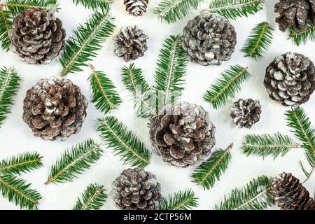 Weihnachten Muster Hintergrund mit schneebedeckten Tannenzweigen und Tannenzapfen auf weißem Hintergrund gemacht. Weihnachten, Neujahr und Winterferien Konzept. Fl Stockfoto