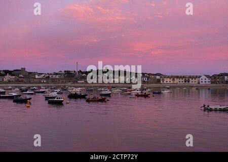 Rosafarbener Himmel über Booten, die von Town Beach, Hugh Town, St Mary's, Isles of Scilly festgemacht sind Stockfoto