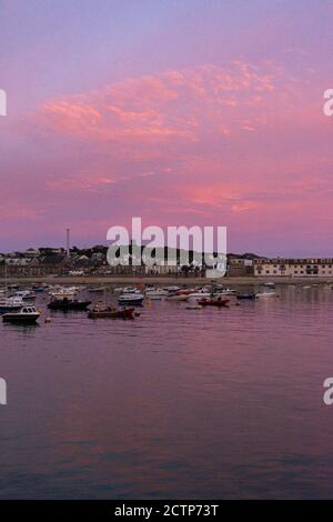 Rosafarbener Himmel über Booten, die von Town Beach, Hugh Town, St Mary's, Isles of Scilly festgemacht sind Stockfoto