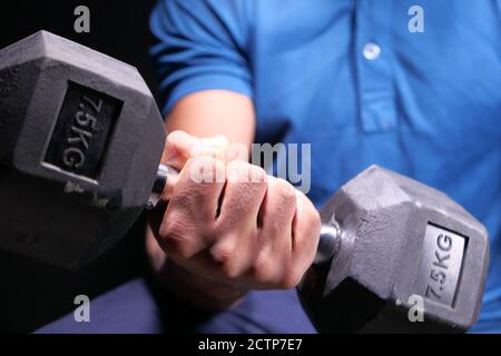 Junger Mann Hand Training mit Hanteln innen. Stockfoto