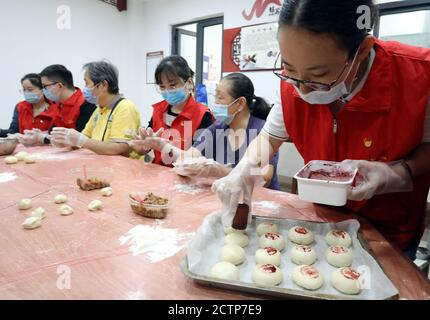 Suzhou, Chinas Provinz Jiangsu. September 2020. Ein Freiwilliger druckt Figuren auf Mondkuchen in einer Gemeinde im Bezirk Gusu in Suzhou, ostchinesische Provinz Jiangsu, 24. September 2020. Es ist eine Tradition, Mooncakes während des Mid-Autumn Festival zu essen, das am 1. Oktober dieses Jahres fällt. Quelle: Hang Xingwei/Xinhua/Alamy Live News Stockfoto