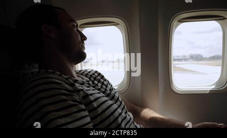 Nachdenklicher Casual-Mann im Flugzeug, der draußen auf Ta wartet Stockfoto