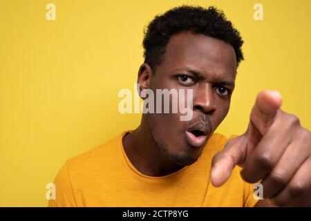 Afroamerikanischer Kerl in gelb casual T-Shirt Entdeckung versteckte Kamera Stockfoto