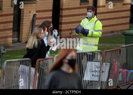 NHS-Mitarbeiter tragen Testkits, während Studenten der Universität Glasgow sich in einem Pop-up-Testzentrum im Studentendorf Murano Street in Glasgow für die Tests anstellen. Stockfoto