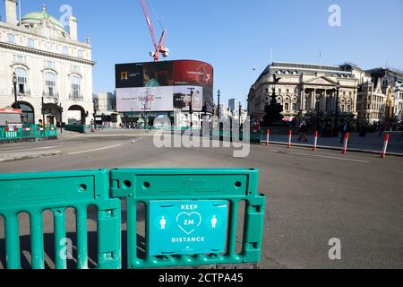 London, Großbritannien. - 20. September 2020: Ein Schild - das Fußgänger zur sozialen Distanz auffordert - vor einem fast menschenleeren Piccadilly Circus im Herzen Londons. Das Bild wurde an einem Wochentag am frühen Morgen aufgenommen, wenn dieser Bereich normalerweise sehr voll wäre. Stockfoto