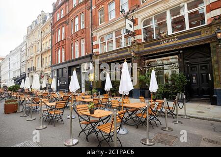 London, Großbritannien. - 21. September 2020: Leere Stühle und Tische im Freien eines Restaurants in Covent Garden. Die Straße wurde vorübergehend Fußgängerzone, um Handel zu helfen, aber die Besucher in der Gegend bleiben niedrig. Stockfoto