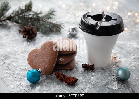 Tasse heißer Kakao mit Marshmallows und weihnachtlicher Lebkuchen in Form eines Herzens auf einem verschneiten Holzhintergrund. Weihnachtskarte. Stockfoto