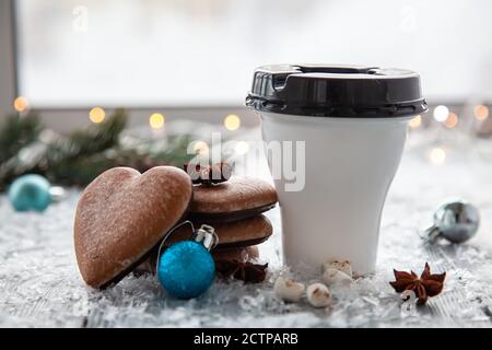Tasse heißer Kakao mit Marshmallows und weihnachtlicher Lebkuchen in Form eines Herzens auf einem verschneiten Holzhintergrund. Weihnachtskarte. Stockfoto