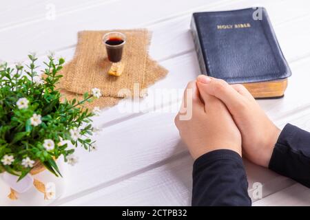 Junge Frau beten und Kommunion nehmen - der Wein und das Brot Symbole von Jesus Christus Blut und Körper mit der Heiligen Bibel. Ostern Passah und Lord Su Stockfoto