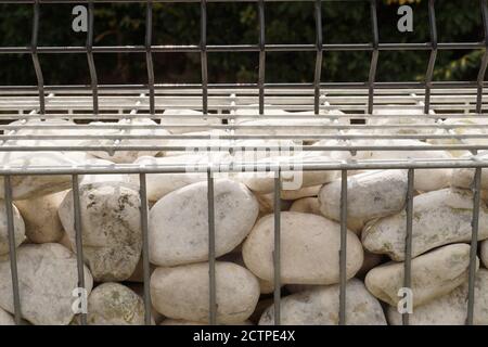 Nahaufnahme eines Zauns aus Gabionen. Behälter gefüllt mit weißen Kieselsteinen. Stockfoto