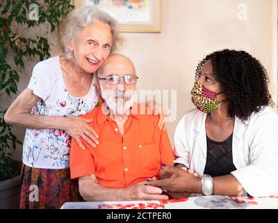 Horizontales Porträt eines afroamerikanischen medizinischen Assistenten hilft ein Zärtlich Paar zu Hause in Zeiten von Covid19 Pandemie Stockfoto
