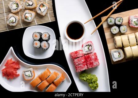 Sushi-Set mit Sauce, Essstäbchen auf schwarzem Tisch Stockfoto