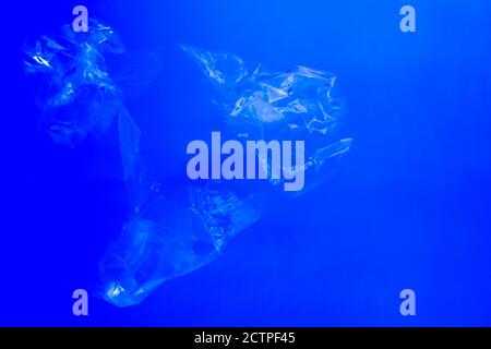 Transparente Plastiktüten, die unter Wasser im blauen Ozean schwimmen, Verschmutzung durch nicht biologisch abbaubaren Plastikmüll, Gefahr für die marine Tierwelt Stockfoto