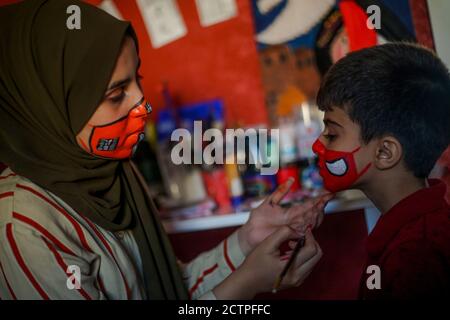 Gaza, Palästina. September 2020. Das palästinensische Mädchen verwendet Wasserfarbe als Maske für das Gesicht eines Jungen.die neunzehnjährige Ranin Al Zeriei malt Maske auf ihr Gesicht in der Stadt Deir Al Balah im südlichen Gazastreifen inmitten der anhaltenden Coronavirus-Pandemie COVID-19. Kredit: SOPA Images Limited/Alamy Live Nachrichten Stockfoto