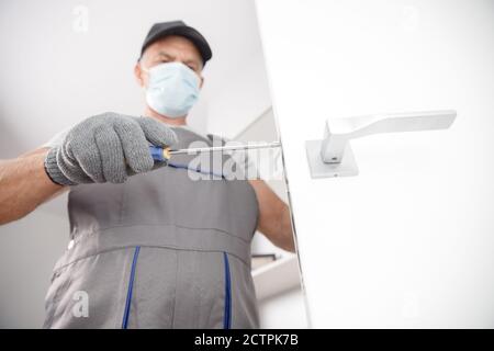 Arbeiter in der medizinischen Maske Verwenden Sie Silikon-Rohr Pistole für die Reparatur und Installation Fenster. Konzept Servicetechniker Stockfoto