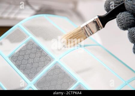 Bürstenreinigung Klimaanlage vor Staub. Arbeiter in Handschuhen und medizinische Maske überprüft Filter Stockfoto