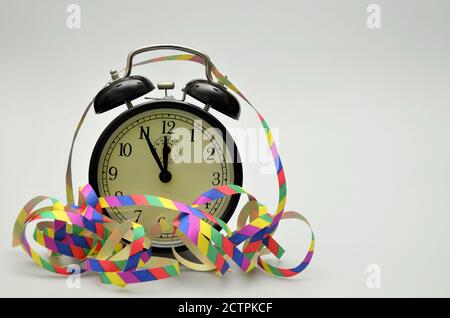 Nahaufnahme eines schwarzen Retro-Weckers mit zwei Glocken, gegen Mitternacht, mit Papierstreamern Stockfoto