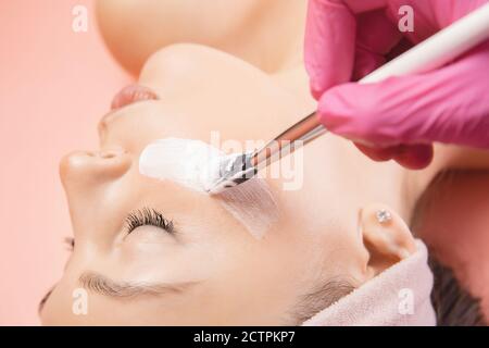 Close-up junge Frau Anwendung Creme für die Hautpflege mit Pinsel. Wellness-Konzept für Schönheitsbehandlungen Stockfoto