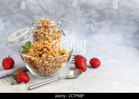Hausgemachtes Müsli mit Erdbeerscheiben in einem Glas. Auf grauem Hintergrund. Vegetarisches Gericht. Gesundes Frühstück. Speicherplatz kopieren. Stockfoto