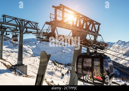 Ischgl, Österreich- 10. Januar 2020: Neue, moderne Großkabinenbahn Silvretta Bahn gegen Skiliftsäule mit Rollengetriebe und hinterleuchteter Sonne Stockfoto