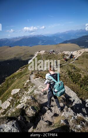 Eine Frau trägt ein Baby auf einem schmalen Bergrücken in den Dolomiten oberhalb von Gröden. Stockfoto