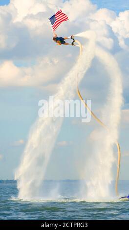 Mann, der auf einem Jet Fly Board am Lake Arlington, Texas fliegt und eine amerikanische Flagge hält. 2020. Stockfoto