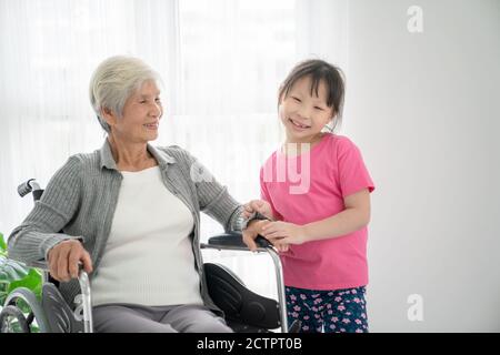 Ältere Patientin im Rollstuhl wartet Arzt mit Enkelkind in Krankenhaus Stockfoto