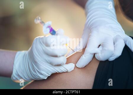Nahaufnahme des Arztes, der den Arm des Patienten mit Grippeimpfstoff injiziert In der Wohnung vor Ort Stockfoto