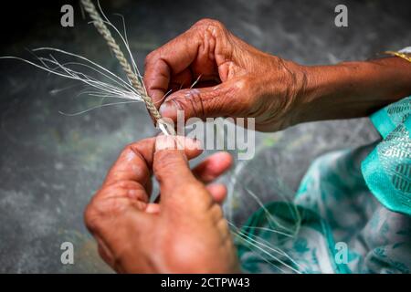 Eine alte Frau macht auf seinen dünnen Händen ein Seil aus der Bananenbaumfaser in Madhupur, Tangail, Bangladesch. Stockfoto