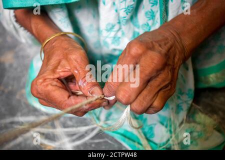 Eine alte Frau macht auf seinen dünnen Händen ein Seil aus der Bananenbaumfaser in Madhupur, Tangail, Bangladesch. Stockfoto