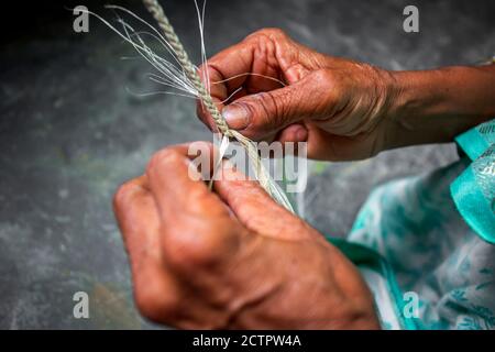 Eine alte Frau macht auf seinen dünnen Händen ein Seil aus der Bananenbaumfaser in Madhupur, Tangail, Bangladesch. Stockfoto