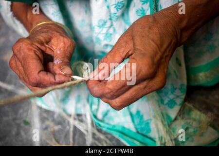 Eine alte Frau macht auf seinen dünnen Händen ein Seil aus der Bananenbaumfaser in Madhupur, Tangail, Bangladesch. Stockfoto