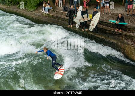 München, Bayern / Deutschland - 17. September 2020: Frau surft auf der stehenden Welle am Eisbach in der Münchner Innenstadt Stockfoto