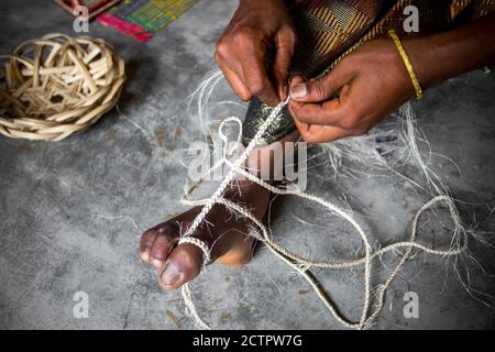 Eine Frau macht aus den Fasern einer Bananenstaude mit Hilfe ihrer Füße auf uralte Weise ein Seil in Madhupur, Tangail, Bangladesch. Stockfoto