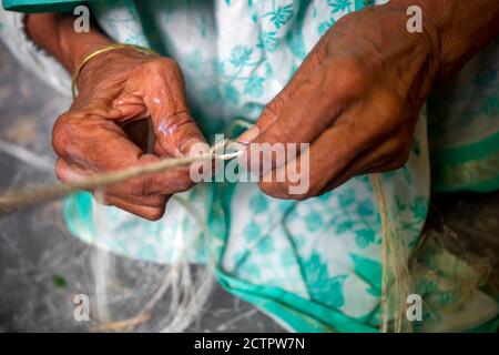 Eine alte Frau macht auf seinen dünnen Händen ein Seil aus der Bananenbaumfaser in Madhupur, Tangail, Bangladesch. Stockfoto