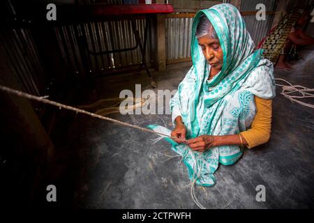 Eine alte Frau macht in Madhupur, Tangail, Bangladesch, ein Seil aus den Bananenbaumfasern in ihren dünnen Händen. Stockfoto