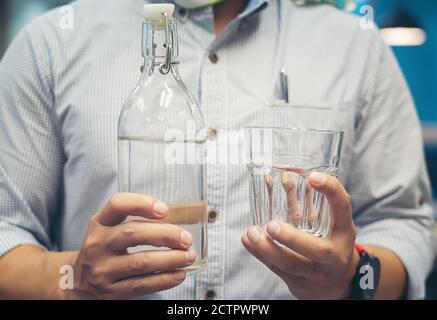Mann hält Flasche Wasser und Glas Stockfoto
