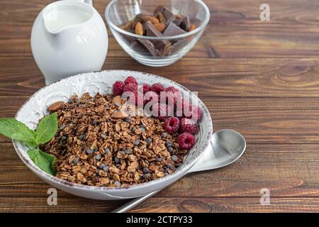 Hausgemachtes Müsli mit Schokolade und Nüssen auf Holzgrund. Vegetarisches Gericht. Gesundes Frühstück. Speicherplatz kopieren. Stockfoto