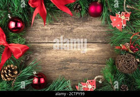 Weihnachtsrahmen mit roten Weihnachtsspielzeug, Bögen und Glaskugeln Kiefer Zweig auf einem natürlichen Holzhintergrund dekoriert. Stockfoto