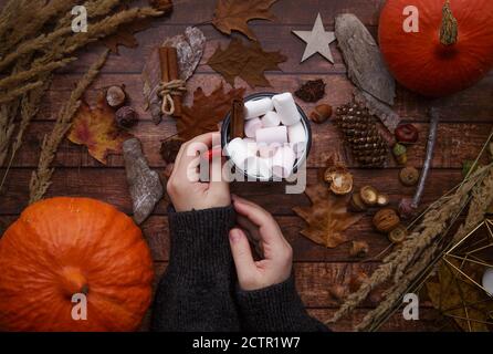 Frau Hände halten rote Tasse Kaffee mit Marshmallows auf Holztisch Stockfoto