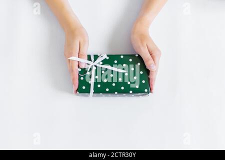 Hände halten ein Geschenk in grüner Verpackung. Stockfoto