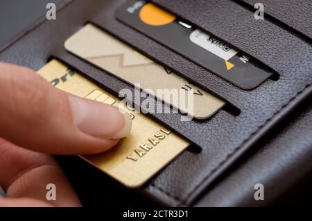 Die Hand der Frauen zieht eine Kreditkarte aus einem schwarzen Geldbörse Stockfoto